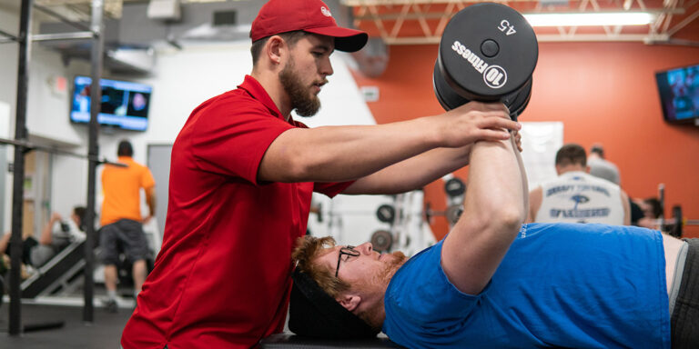 a personal trainer guiding a client during his workout at the Springfield club