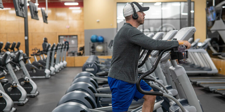 un hombre usando una máquina de cardio en el club de la Universidad