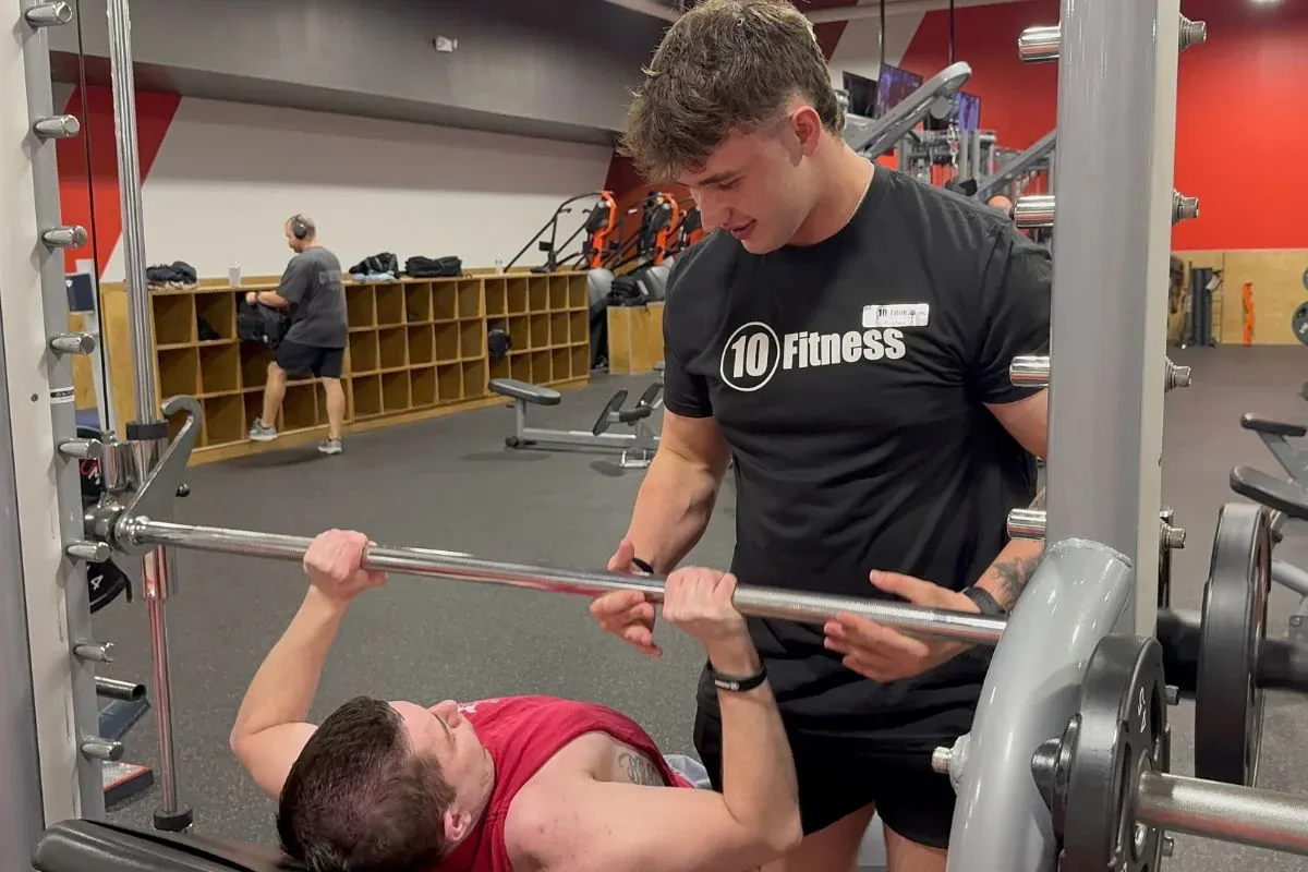 Beginner man starting his workout routine at 10 Fitness gym with dumbbells and exercise equipment
